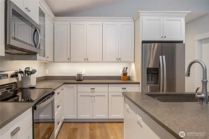 Well-equipped kitchen with stainless steel refrigerator, range, microwave, and dishwasher, surrounded by generous cabinetry and counter space.