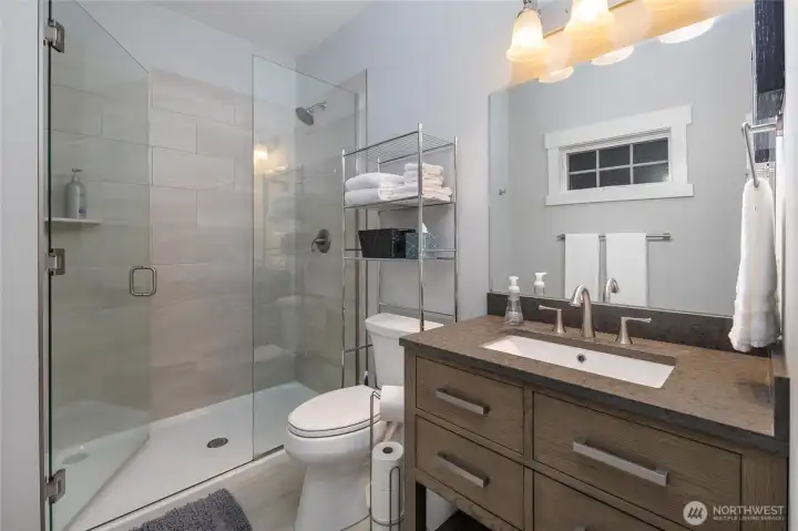 Modern ensuite bathroom with glass walk-in shower, stylish tile surround, and sleek vanity with ample storage.