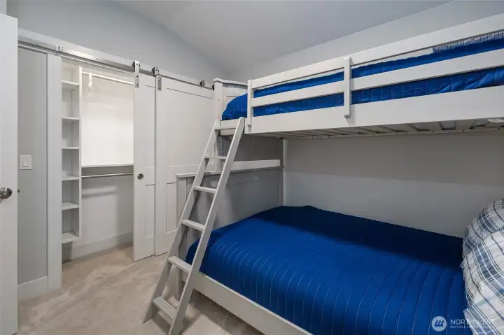 Comfortable guest room with sliding barn-door closet providing convenient storage and a modern touch.