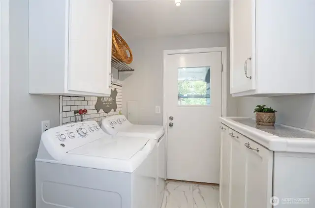 Well-appointed utility room featuring extra cabinetry and counter space, with an exterior door that opens directly to the patio.