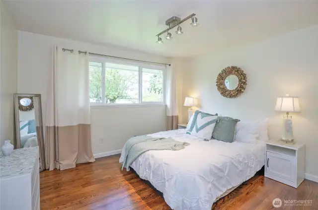 The primary suite features track lighting and a large window that fills the space with natural light. Beautifully refinished hardwood floors add warmth and charm.