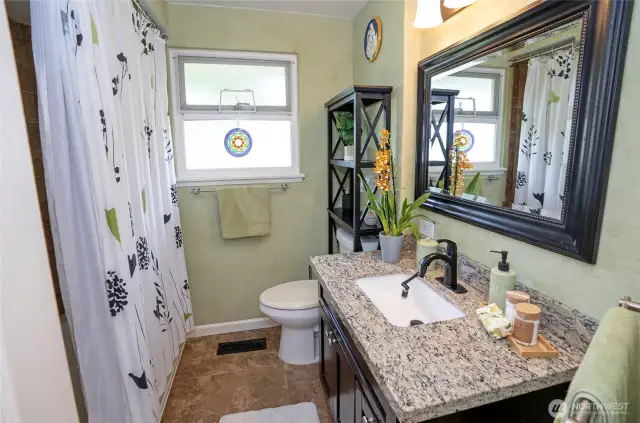 The main full bath is beautifully updated with a sleek vanity and modern countertop, combining style and functionality.