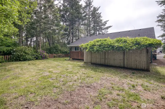 Large partially fenced backyard with mature landscaping