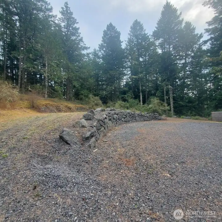 Lot has an upper and lower level with a rock wall. Surrounded by mature trees for privacy.