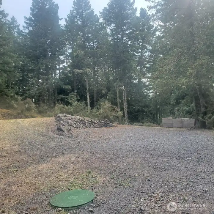 View from pump house shows rock wall between upper and lower areas of lot. Privacy fence at each end of lot.