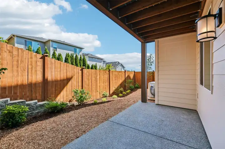 Covered patio off of lower level bonus room overlooks a fully fenced/landscaped sanctuary.