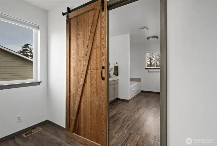 Sliding barn door from primary bedroom into ensuite bathroom.