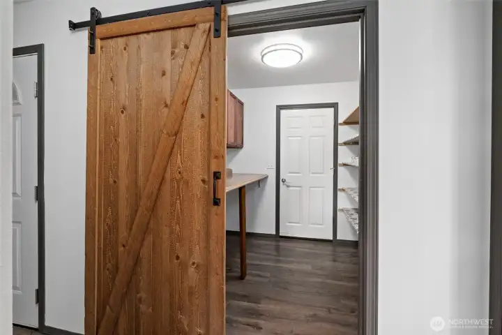 Sliding barn door into laundry/pantry room with door to garage.