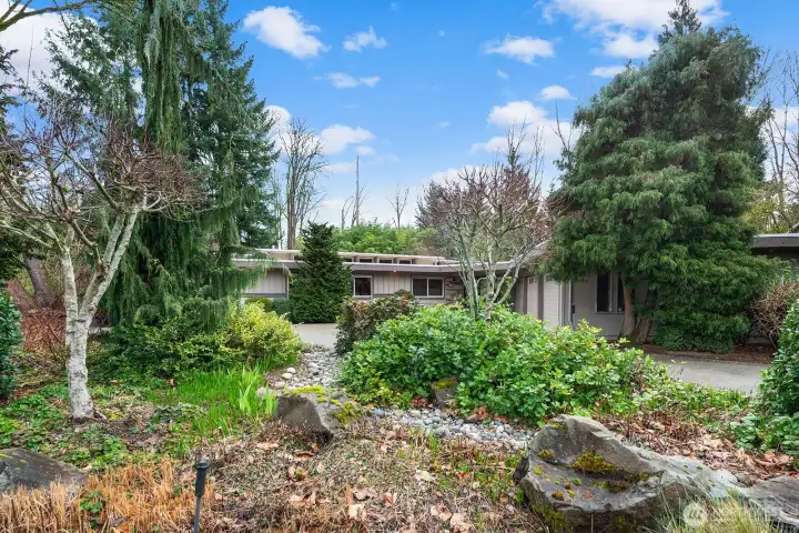 Intentional native landscaping of rocks, brush, trees, grasses, and flowers are featured throughout the property.