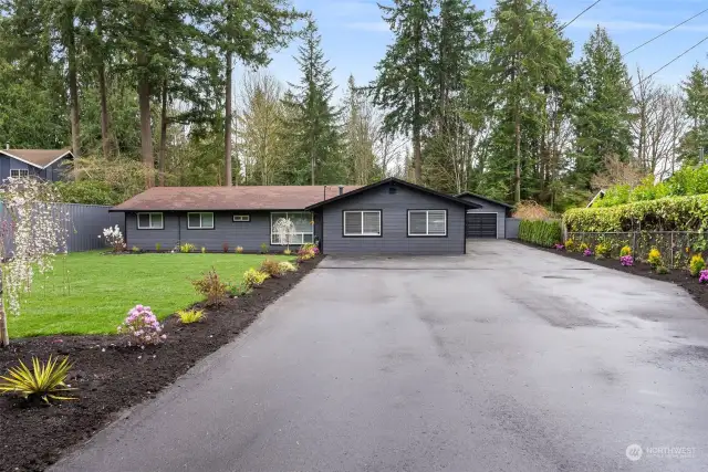 Long asphalt driveway entrance, lots of parking, and with beautiful landscaping on either side.