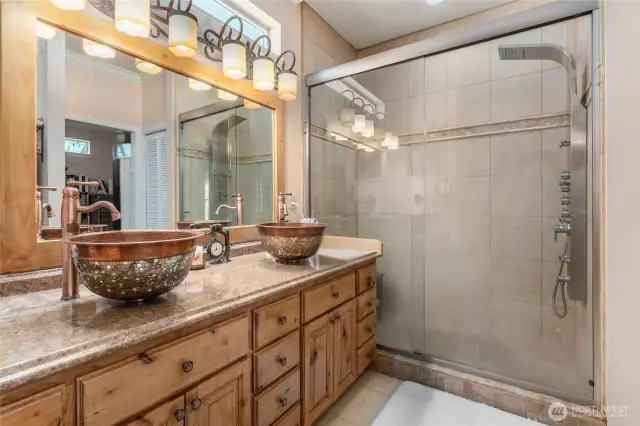 Bathroom features warm copper sinks paired with a spacious walk-in shower