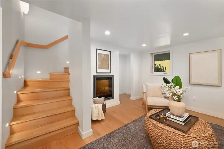 Custom staircase with accent lighting leads downstairs to the family room with an electric fireplace and engineered hardwoods. Custom staircase with accent lighting leads downstairs to the family room with an electric fireplace and engineered hardwoods.