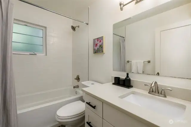 Nicely remodeled full bathroom with west facing window, subway tiles, and quartz counters.