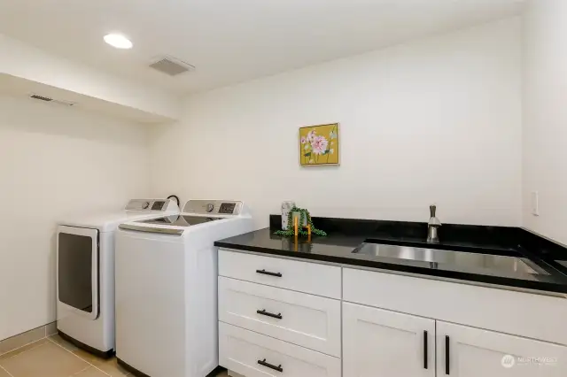 At the far end of the hallway, you’ll find the large laundry room with quartz counters and stainless-steel sink.