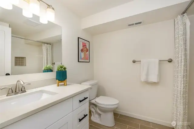 Next to the laundry room, you’ll find the ¾ bath with quartz counters, tile floors and a subway tile shower surround.