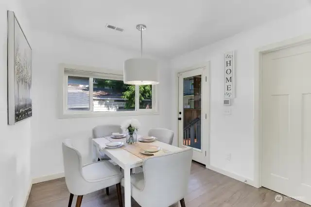 Inviting dining nook with shiplaps accent wall and glass door to access charming covered back deck and paved patio.