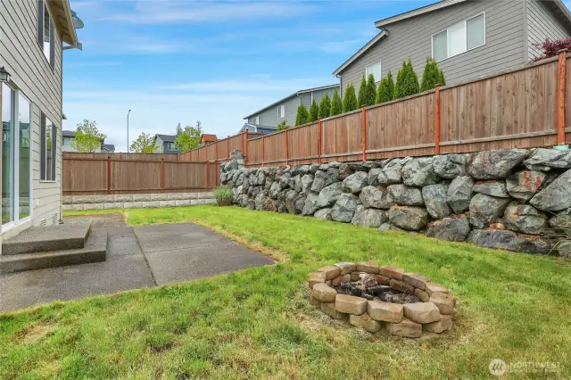 Nice rock retaining wall and everone enjoys a little backyard fire pit!