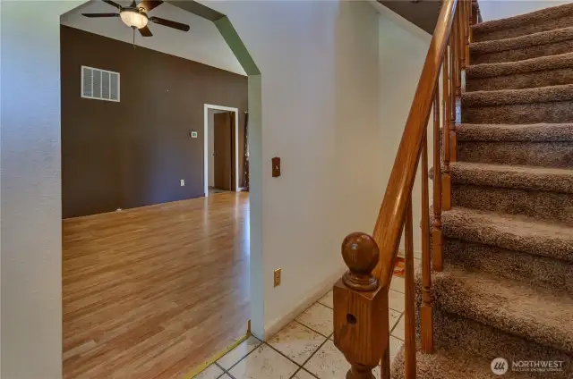 Warm and welcoming entryway with tile floors, plush carpeted stairs, and a peek into the open living space your next chapter starts right here