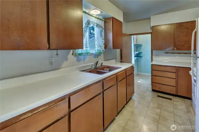 Retro charm meets functionality in this galley-style kitchen—offering tons of cabinet space, ample counters, and a cozy window view over the sink