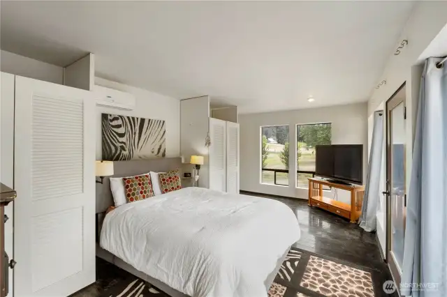 Spacious and serene primary bedroom featuring large picture windows with peaceful views of the pond and surrounding landscape.