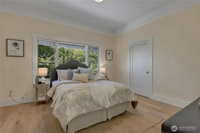 Primary bedroom with two walk-in closets. Tall ceilings with crown molding. Note full wood-wrapped windows.  Entire home just painted!  Fresh and ready for you!  Mini split for all year comfort.