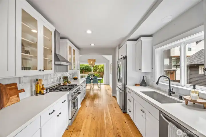 Modern kitchen design with quartz counters, glass cabinets and wide-plank oak flooring.