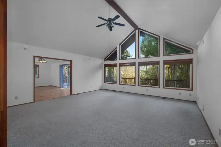 Living room with vaulted ceilings and wall of windows.