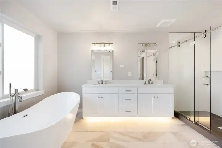 Primary bath has a separate toilet room, tiled, a free standing tub under a frosted glass window, double sink vanity with under cabinet lighting!