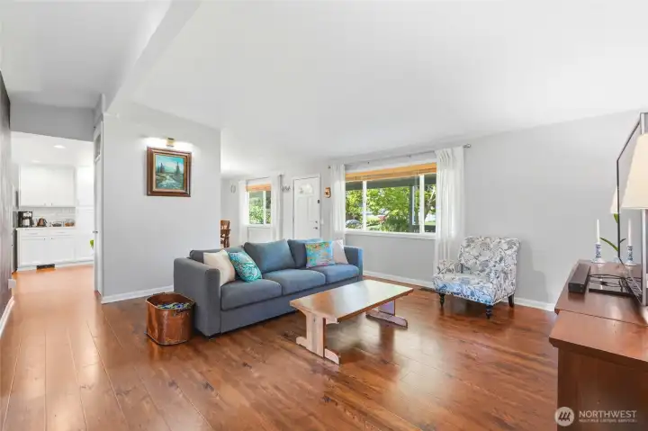 Open concept living space with warm flooring and easy flow into the kitchen and entry, perfect for everyday living.