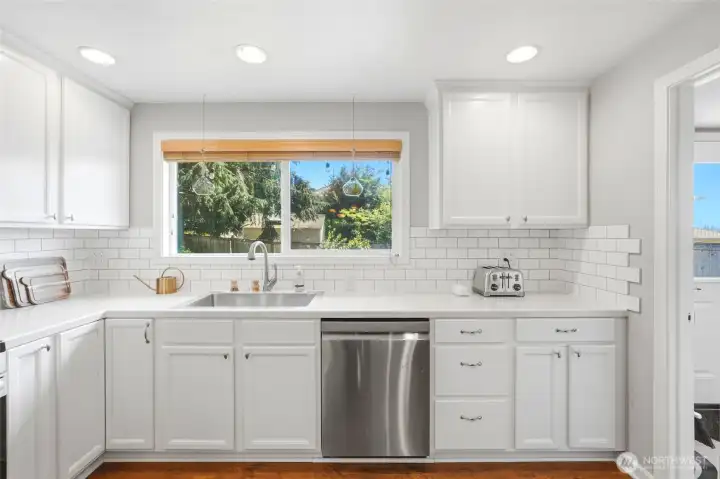 Light filled kitchen with large window overlooking the backyard, bringing in natural light and a pleasant view.