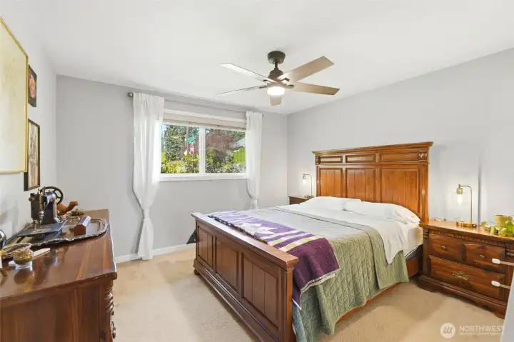 Spacious primary bedroom with large window, abundant natural light, and room for full furniture set.