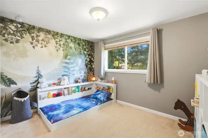 Charming bedroom featuring a custom wallpaper mural and flexible space for play, sleep, or home office.