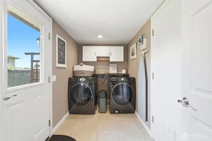 Dedicated laundry room with side by side washer and dryer, extra storage, and convenient garage and exterior access.