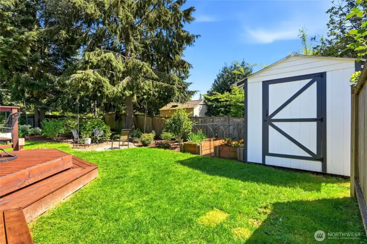Private backyard with lush lawn, garden space, and storage shed for tools and outdoor gear.