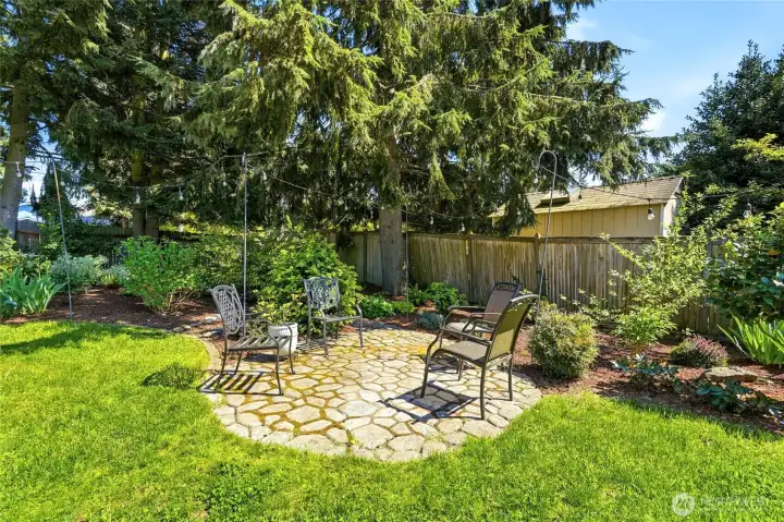 Charming stone patio surrounded by mature landscaping, perfect for quiet mornings or evening gatherings.