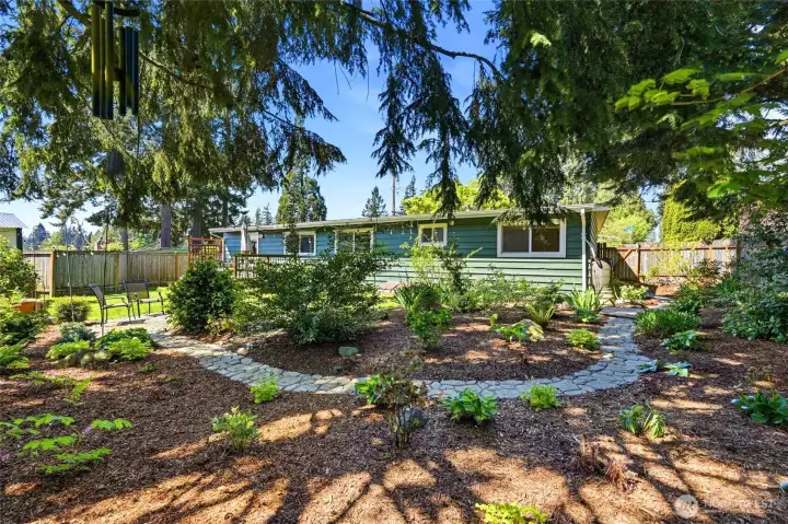 Beautifully landscaped backyard with winding stone pathways, mature trees, and a peaceful, park-like setting.