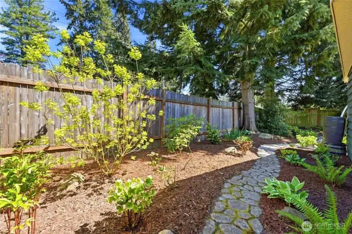 Charming stone walkway surrounded by lush greenery and established landscaping.