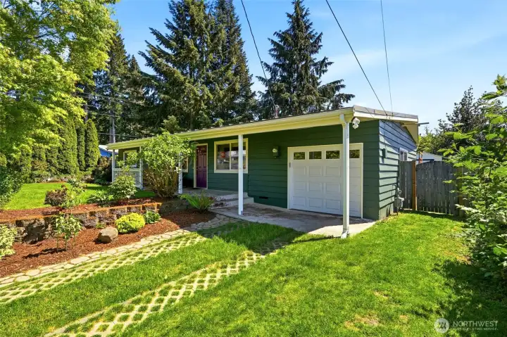 Welcoming front exterior with covered entry, mature landscaping, and convenient garage parking.