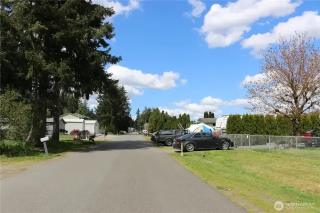 View of the paved street from another angle—home is located just to the right, behind the chain-link fence.
