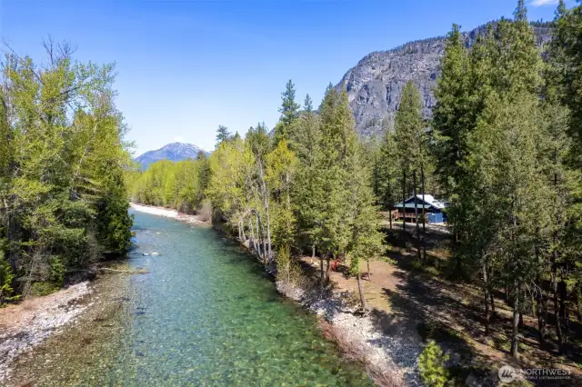 Incredible riverfront setting with crystal-clear water, towering evergreens, and panoramic mountain views. This peaceful, private retreat offers direct access to nature and endless beauty just outside your door.