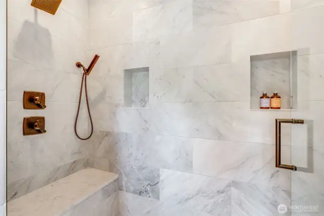 Luxurious walk-in shower with Carrara marble, heated floor, three shower heads, product shelves and a shower seat. Great place to start your day!