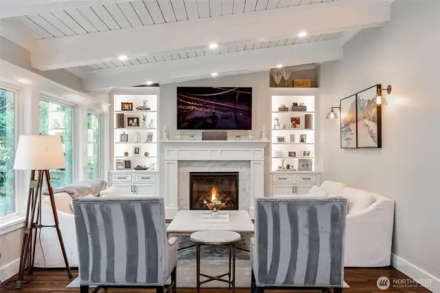 Cozy gas fireplace surrounded by Carrara marble and custom cabinetry.