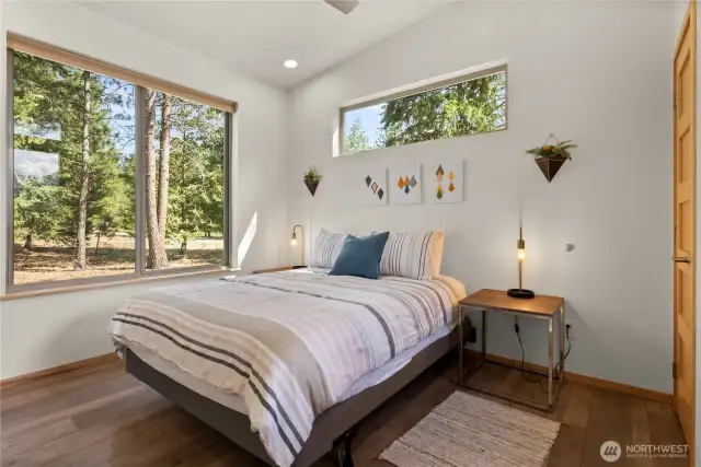 Primary bedroom with serene forest views and modern finishes.