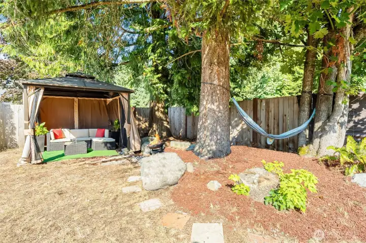 Fully fenced and landscaped yard w/ corner gazebo to lounge in and side patio to dine in.