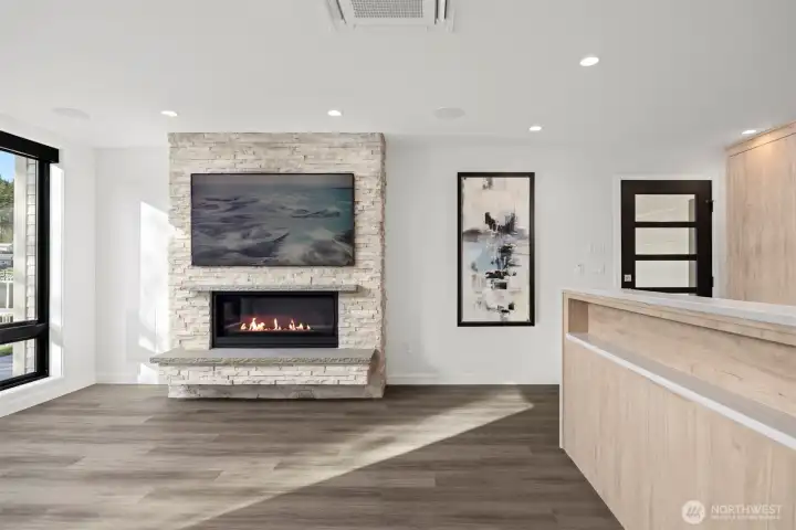 Looking across the living room with the gas fireplace that has a television mounted above that looks like art, when not in use.