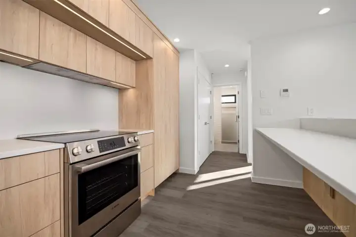 Looking through the kitchen toward the 3/4 bath beyond the laundry closet to the left beyond the concealed Thermador refrigerator.