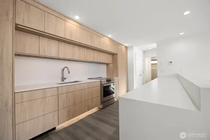 The sleek custom-built cabinets and quartz counters are just stunning and the lighting accents their contiguous wood grains.