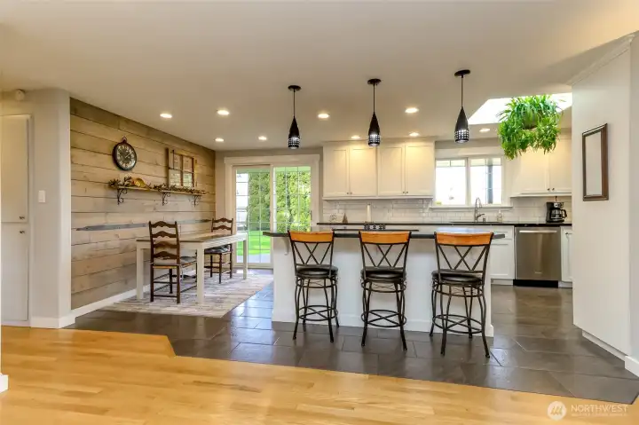 The chef ready eat-in-kitchen boasts elegant cabinets and countertops and stainless steel appliances. A shiplapped accent wall creates a welcoming, cozy feel, enhanced by a skylight that brings in an abundance of natural light