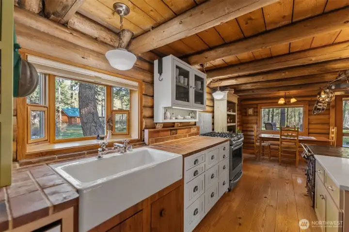 Country kitchen features a deep farm sink and custom cabinets with brick countertops. The craftsmanship is high quality and the effect is delightful.