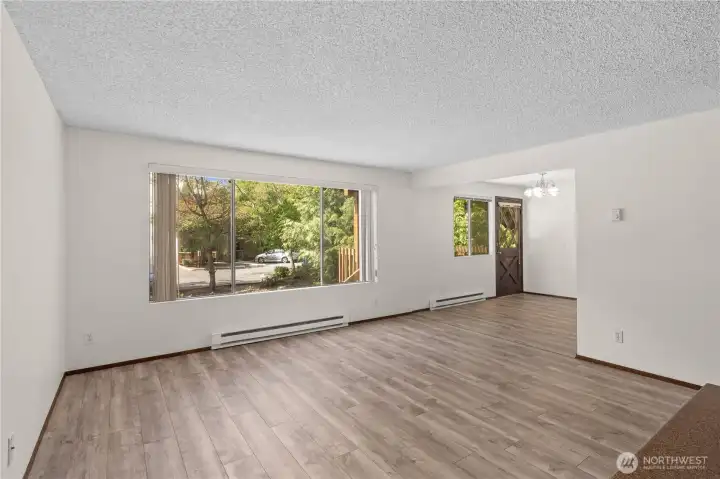 Unit A living room with large window for natural light. Brick fireplace is across from the window. Unit A living room with large window for natural light. Brick fireplace is across from the window.